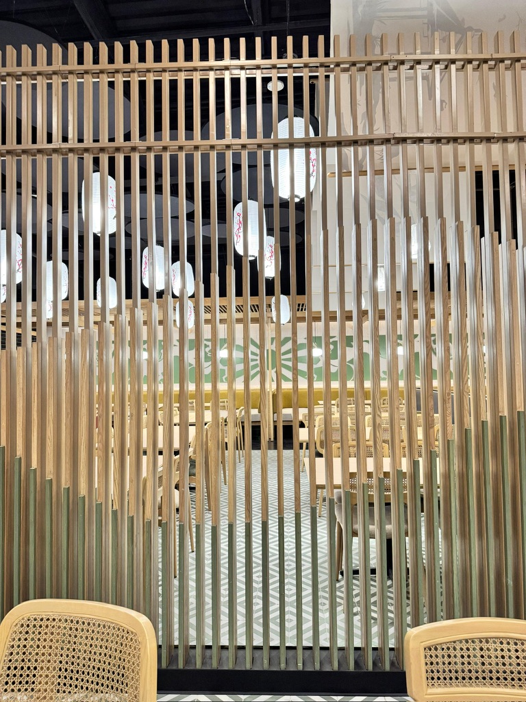 Ginsoy Houston — the timber-slat screen separates two dining zones, lanterns visible through the gaps