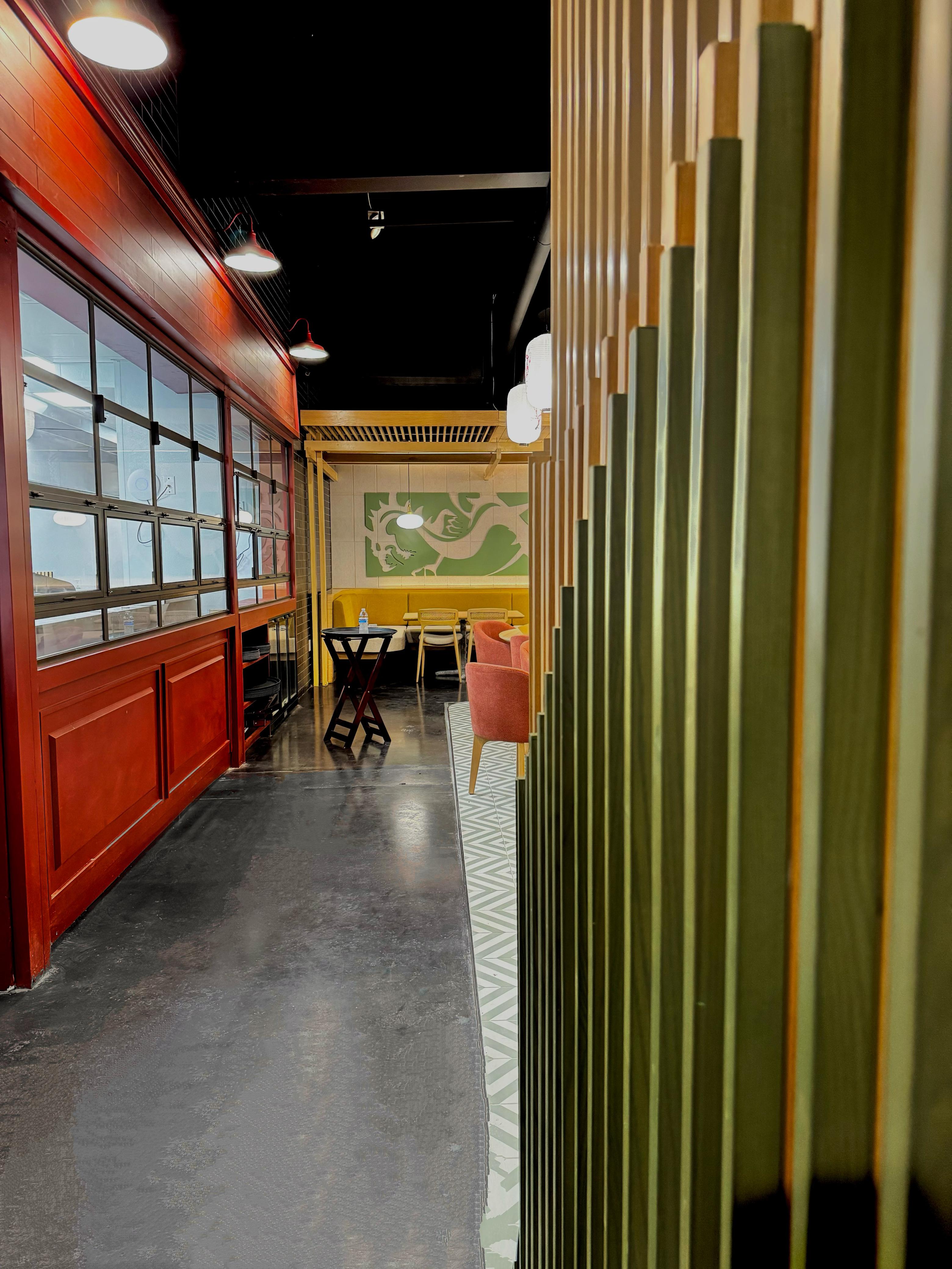 Ginsoy Houston — semi-private dining nook with the sage-green dragon seal panel framed by a vertical timber-and-metal screen