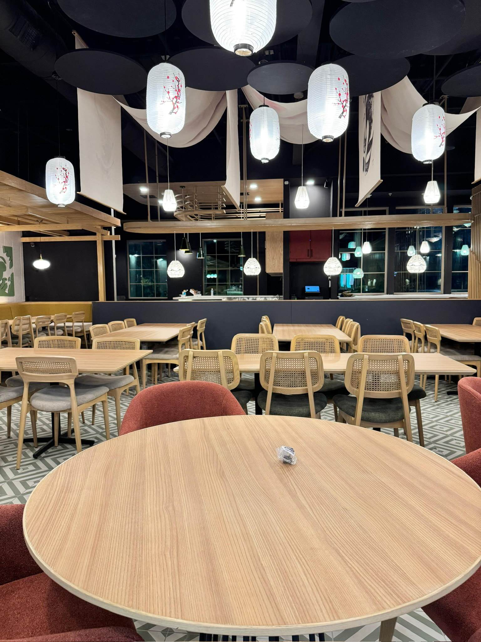 Ginsoy Houston — overhead lanterns float above maple chairs and round dining tables