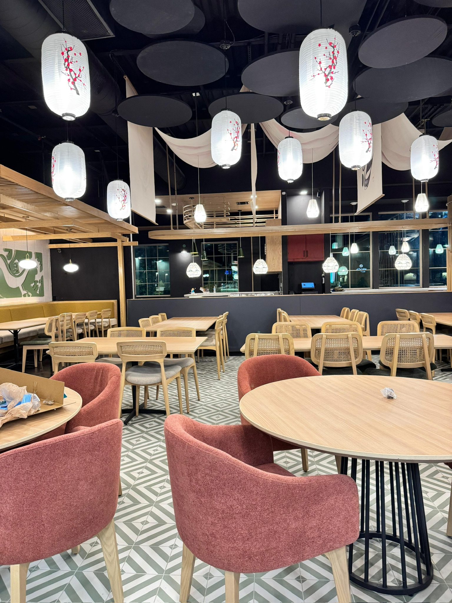 Ginsoy Houston — round timber tables with rose-pink tub chairs sit beneath the cherry-blossom paper lanterns