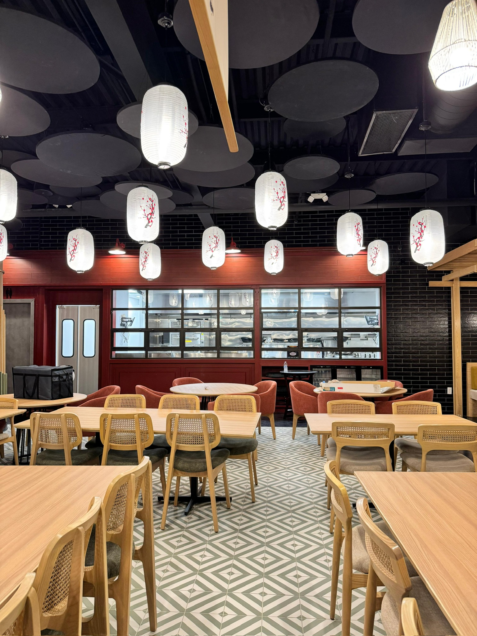 Ginsoy Houston — wide view of the main dining hall under a canopy of paper lanterns with the open kitchen pass behind